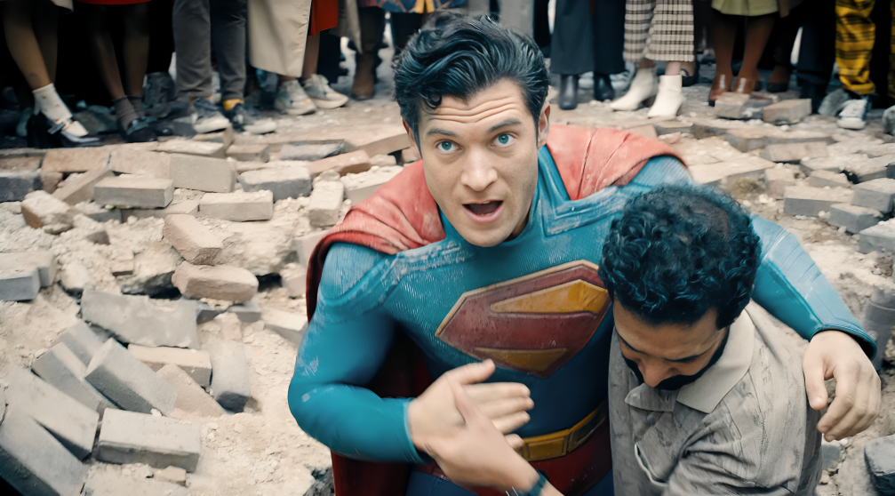 Man lifting fallen Superman from the road with debris around.
